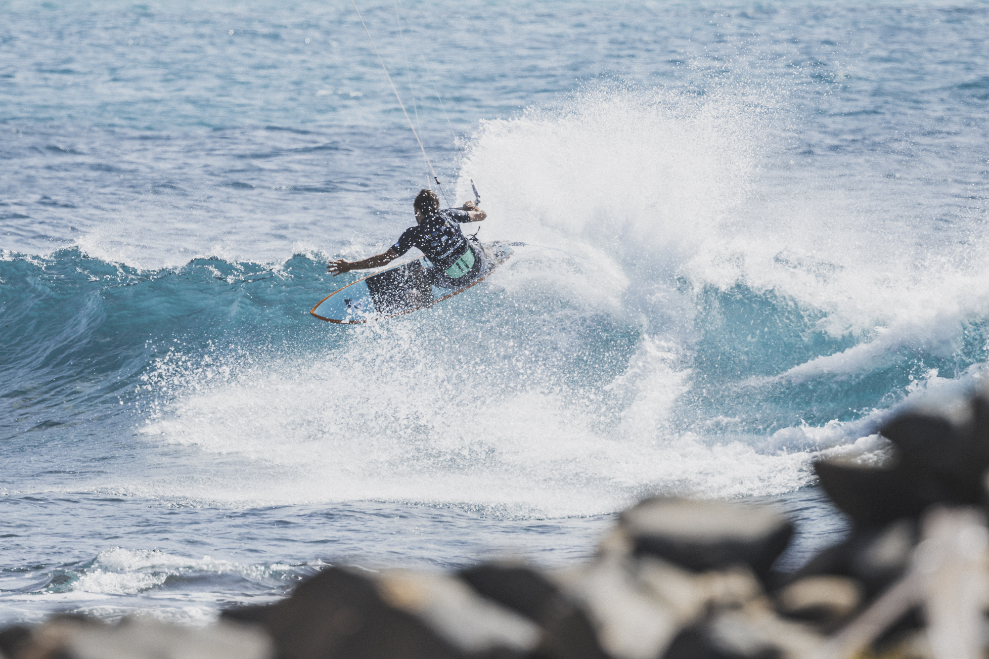 Kiter trazando una regata sobre olas con gran abanico de spray